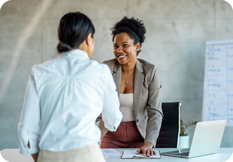 2 women shaking hands at desk