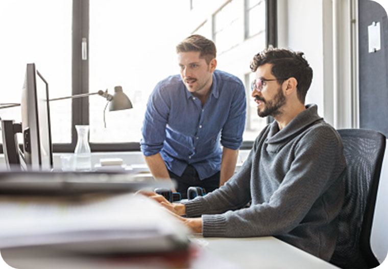 2 Men looking at computer screen at desk
