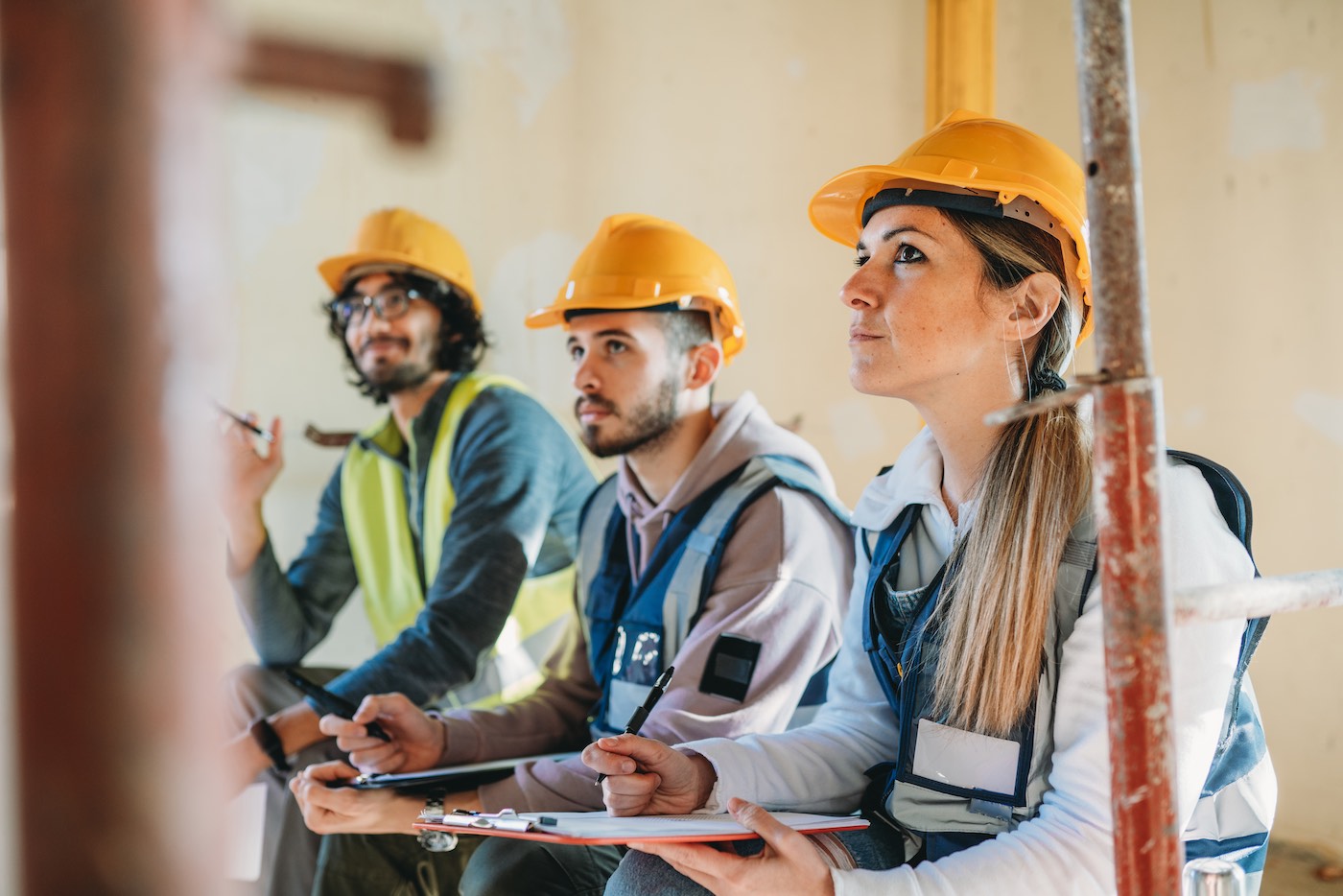 Trade school students in hard hats at construction site learning from instructor